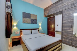 Une chambre à coucher comprenant un lit, des tables de chevet, une lampe fixée au mur, une armoire et un élément décoratif mural.