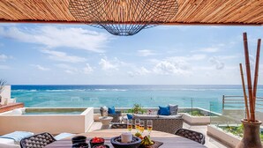 A wooden table with bowls and glasses, overlooking a beach with a clear view of the ocean. - Tulum Beachfront Penthouse – Rooftop & Pool (Tulum)
