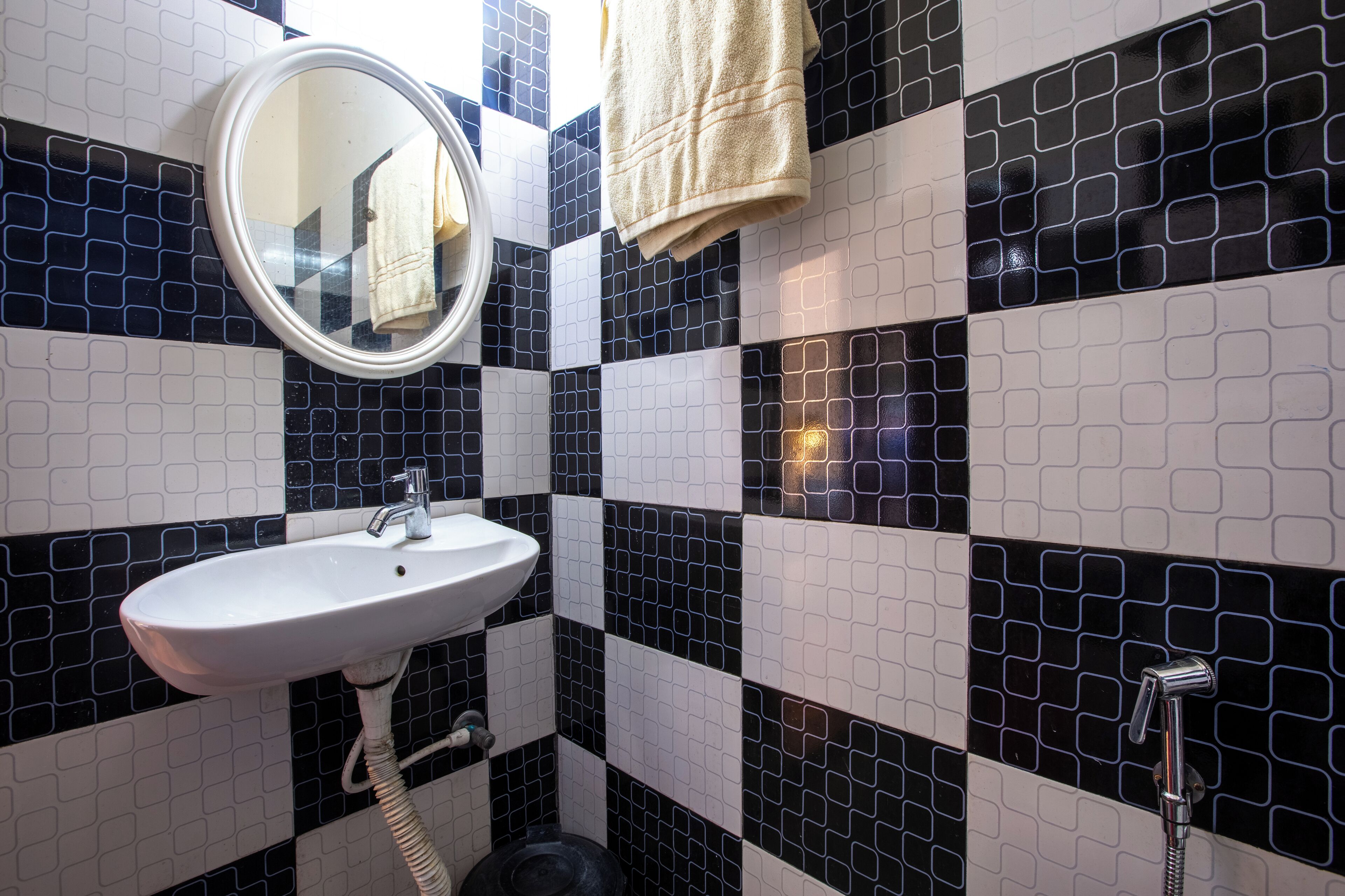 A bathroom with a white sink, a round mirror, and a towel hanging on the wall.