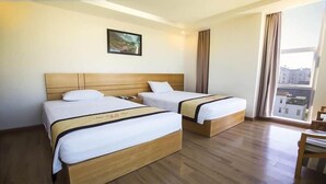 Habitación de hotel con dos camas, cabeceros de madera, un ventanal con cortinas y un cuadro enmarcado en la pared.