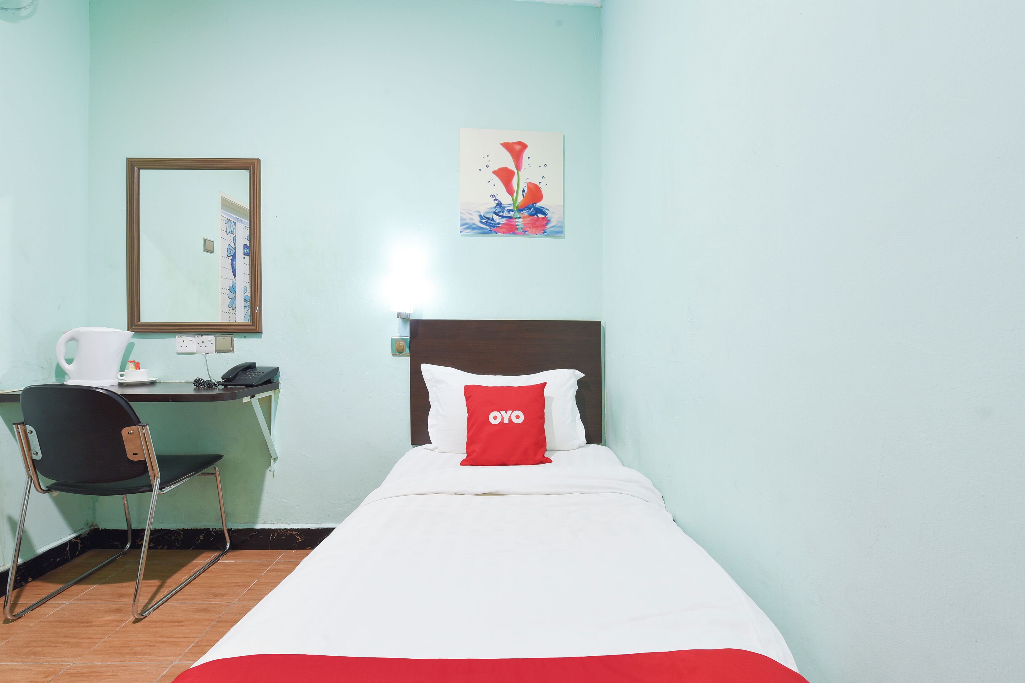 Una habitación de hotel con cama, un escritorio con silla, cafetera y espejo en la pared.