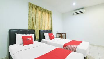 A hotel room with two beds, each with a red and white bedspread, a small table, and an air conditioning unit on the wall.