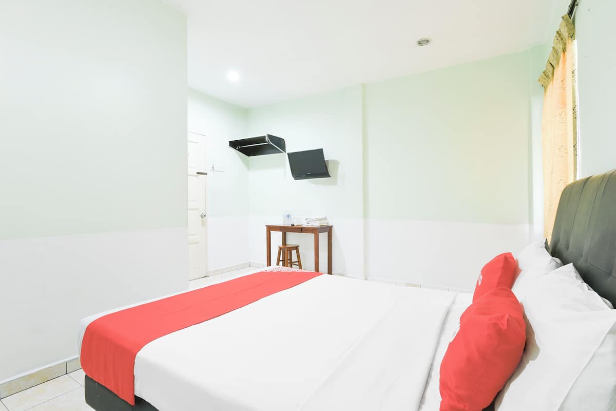 Een hotelkamer met een bed, een bureau en een wandgemonteerde flatscreen televisie.