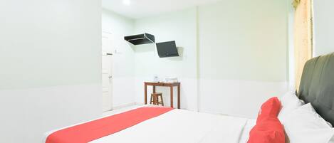 Une chambre d’hôtel équipée d’un lit, d’un bureau et d’un téléviseur à écran plat fixé au mur.