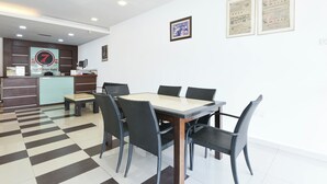 Un vestíbulo de hotel con mostrador de recepción, mesa de comedor y sillas, y certificados enmarcados en la pared.