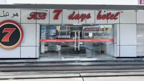 Entrada de hotel con un llamativo letrero que dice '7 días' y un gran símbolo del número 7.