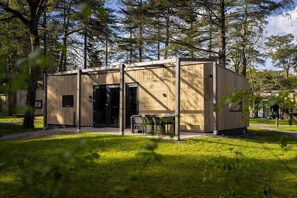 A modern wooden cabin with a door, windows, and a table with chairs.
