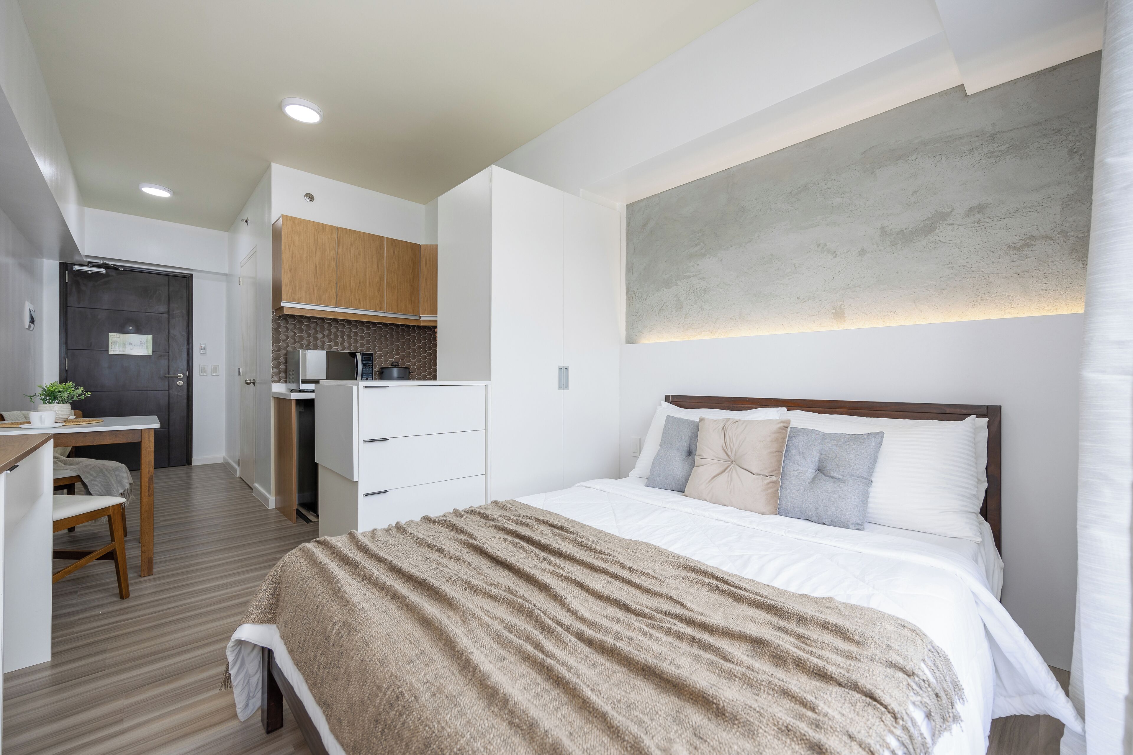 Un dormitorio moderno con una cama grande, un escritorio y una kitchenette.