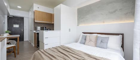 Un dormitorio moderno con una cama grande, un escritorio y una kitchenette.