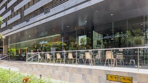 A modern building with a glass facade, outdoor seating area, and a sign for 'Jollibee'.