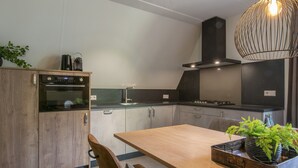 Eine moderne Küche mit Holzausstattung, einem eingebauten Ofen, einem Gasherd und einem Essbereich mit Holztisch und Stühlen.