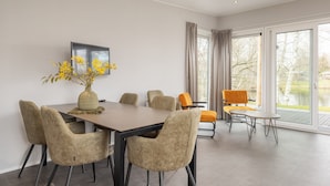 A modern dining area with a table, chairs, and a vase of yellow flowers.