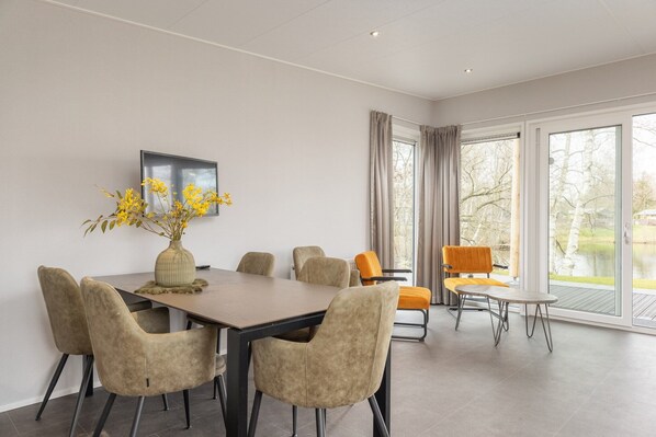 A modern dining area with a table, chairs, and a vase of yellow flowers.