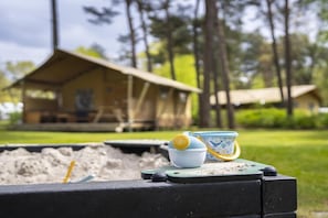 A campsite with a tent and a table with a cup and spoon.