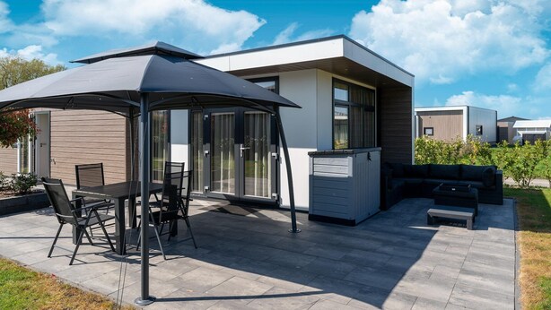 Un patio moderno al aire libre con una mesa de comedor y sillas, una zona de estar cubierta y un banco integrado.