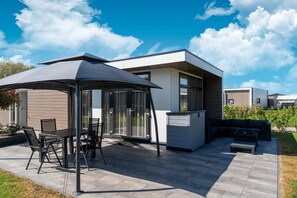 Un patio moderno al aire libre con una mesa de comedor y sillas, una zona de estar cubierta y un banco integrado.