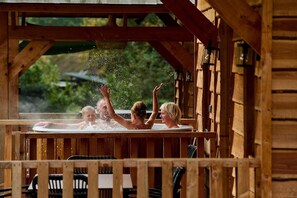 Ein Holz-Whirlpool, in dem vier Personen das Wasser genießen.