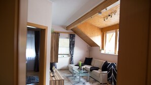 A living room with a glass coffee table, a sofa, and a wooden cabinet. - Cosy apartment in Arnoldstein (Arnoldstein)