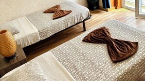 A room with two beds, a window with curtains, a wooden floor, and a small trash bin. - Room-7lisbon Downtown Private Bedroom Wi (Lisbon)