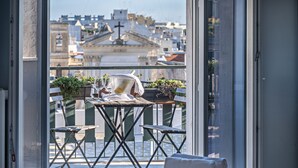 A balcony with a table, chairs, and potted plants.