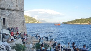 A coastal scene with a stone building and a dining area overlooking the sea. - Villa madonna della Strada A5 (Dubrovnik)