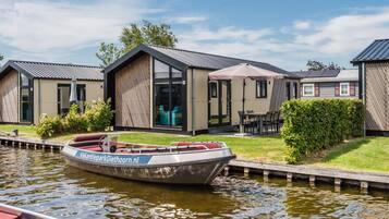 A modern houseboat with a label 'VakantieparkGiethoorn.nl' docked at a canal.