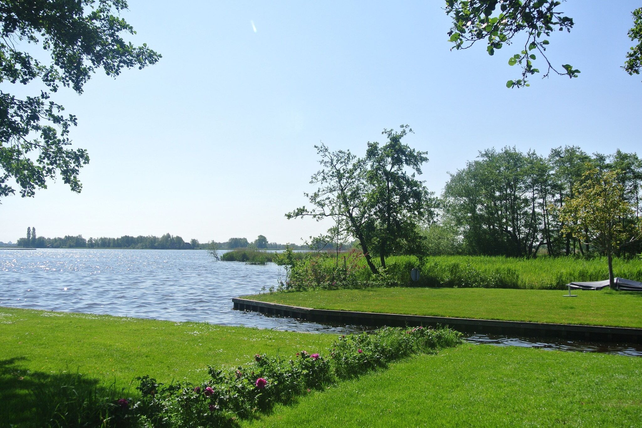 A riverside park with a grassy area, trees, and a dock.