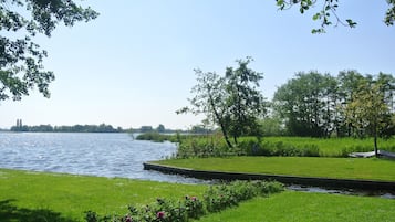 A riverside park with a grassy area, trees, and a dock.