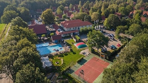 An aerial view of a residential area with houses, a swimming pool, and a tennis court.