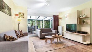 Un salon moderne avec un canapé, une table basse, un téléviseur et une étagère en bois.
