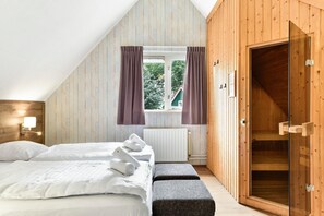 Ein Schlafzimmer mit einem Bett, zwei Nachttischen, einem Fenster mit Vorhängen, einem Heizkörper und einer Holztür.