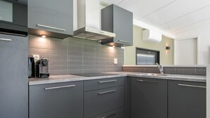 A modern kitchen with grey cabinets, a stainless steel sink, and a built-in oven. - Air-Conditioned Chalet near Eindhoven (Mierlo)