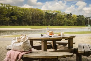 A picnic table with a bag, a bottle, a cup, and a hat on it. - Air-Conditioned Chalet near Eindhoven (Mierlo)