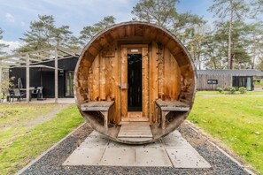 A large wooden barrel-shaped structure with a door and two benches on either side. - Chalet near Eindhoven with Private Sauna (Mierlo)