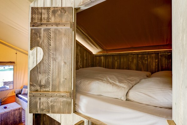 A compact, wooden interior with a bunk bed and a small seating area with cushions.