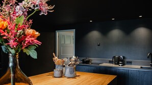 Une cuisine moderne avec une table en bois, un vase de fleurs et des ustensiles de cuisine.