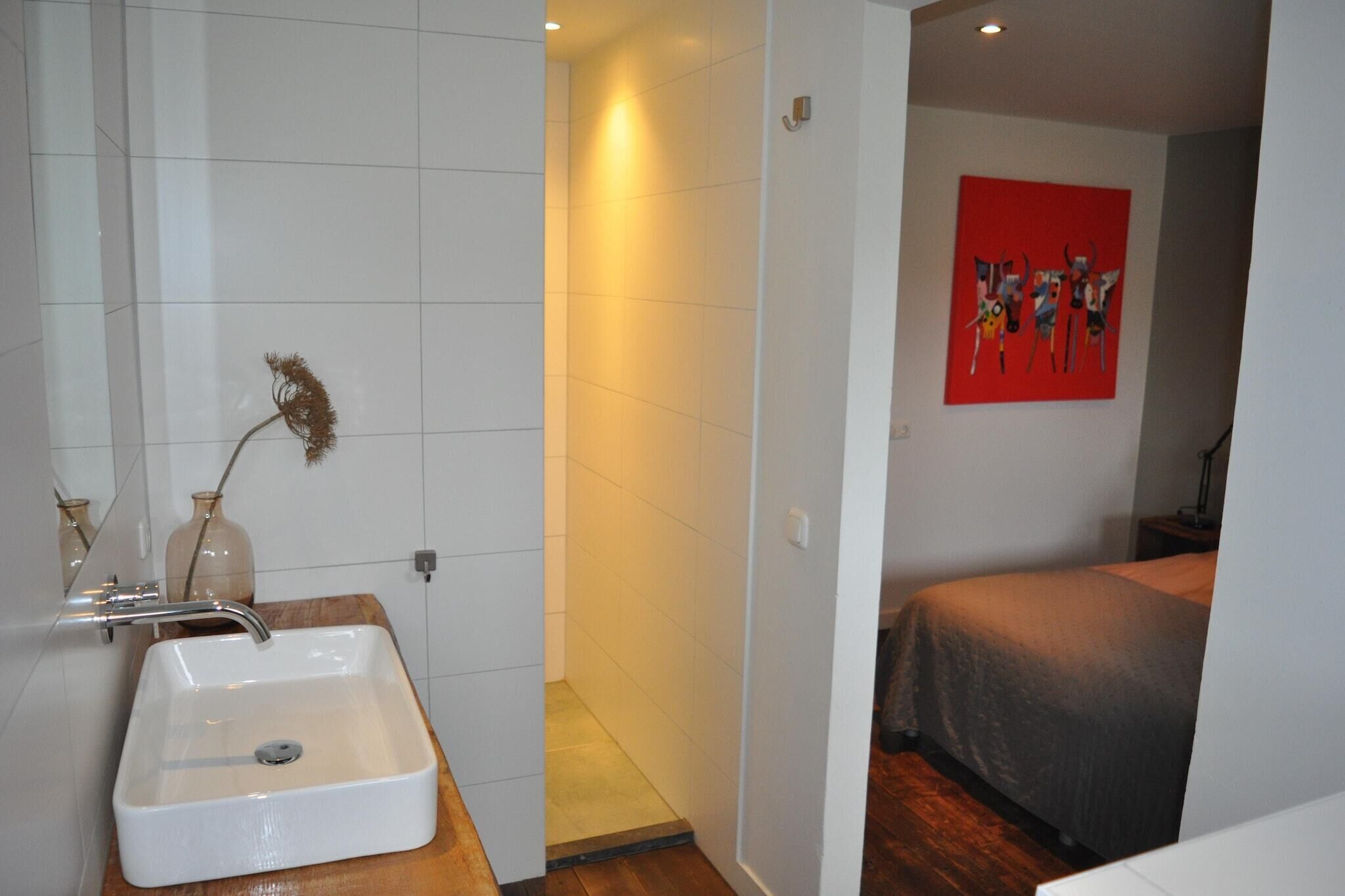 Een badkamer met een wit wastafel, een spiegel en een rode afbeelding aan de muur.