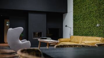 Ett modernt vardagsrum med en grön vägg, en öppen spis och moderna möbler.