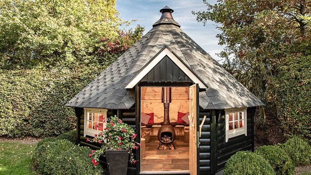 Une cabane en rondins avec une cheminée, uneâtre et une porte donnant sur l’intérieur.