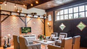 Un salon confortable avec des canapés en cuir, un téléviseur à écran plat et un mur en briques.