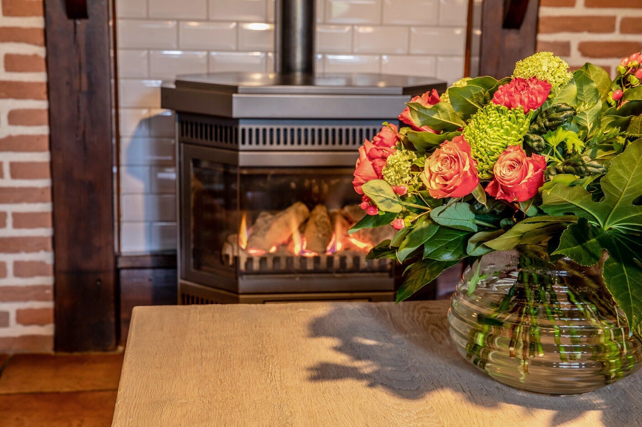 A fireplace with a modern design, a clear glass front, and a brick wall backdrop.