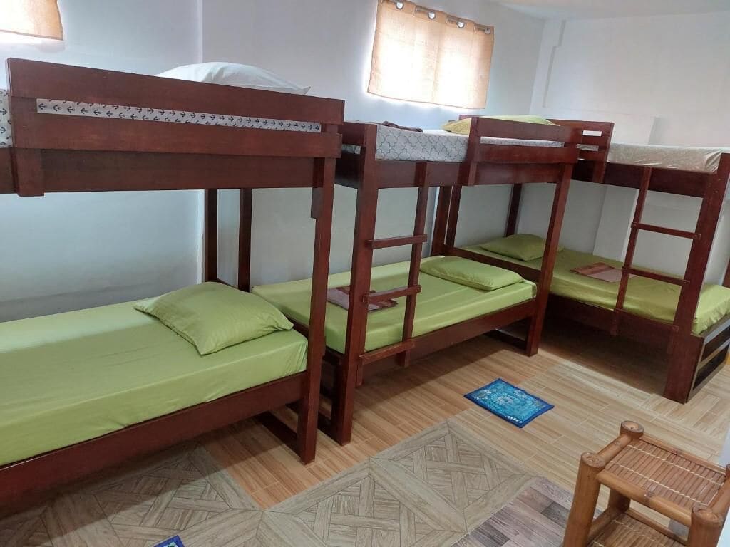Une chambre avec des lits superposés, une fenêtre avec des rideaux et un sol à motifs.