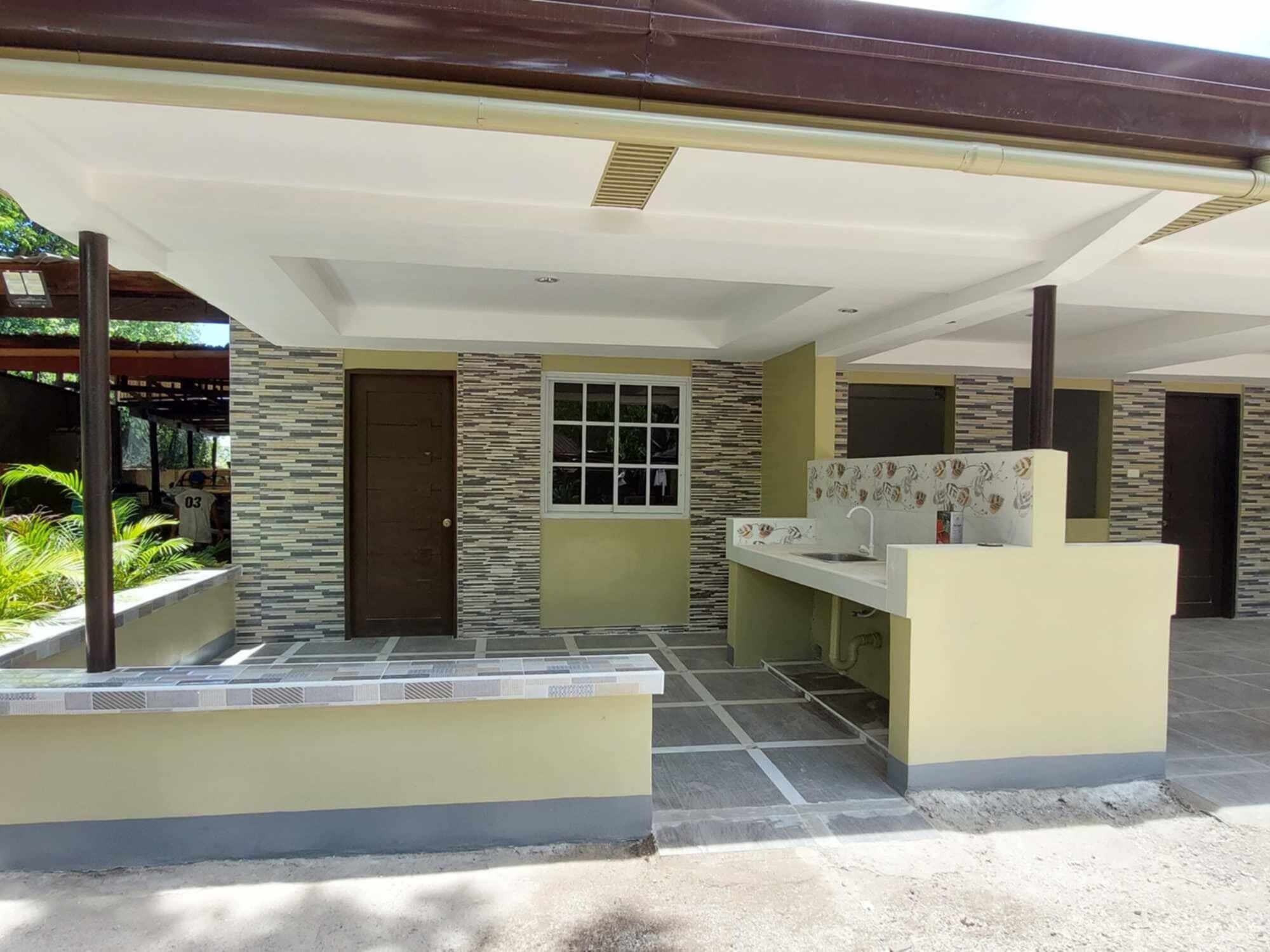 A covered outdoor area with a kitchen counter, a door, and a window.