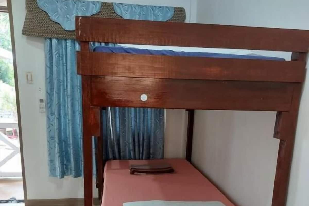 Un lit superposé avec une structure en bois, un matelas rose et un rideau bleu.