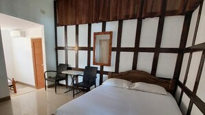 Une chambre à coucher avec un lit en bois, un bureau avec une chaise, un miroir et une porte.