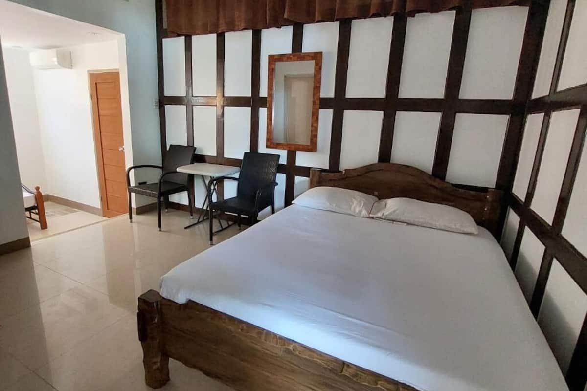 Une chambre à coucher avec un lit en bois, un bureau avec une chaise, un miroir et une porte.