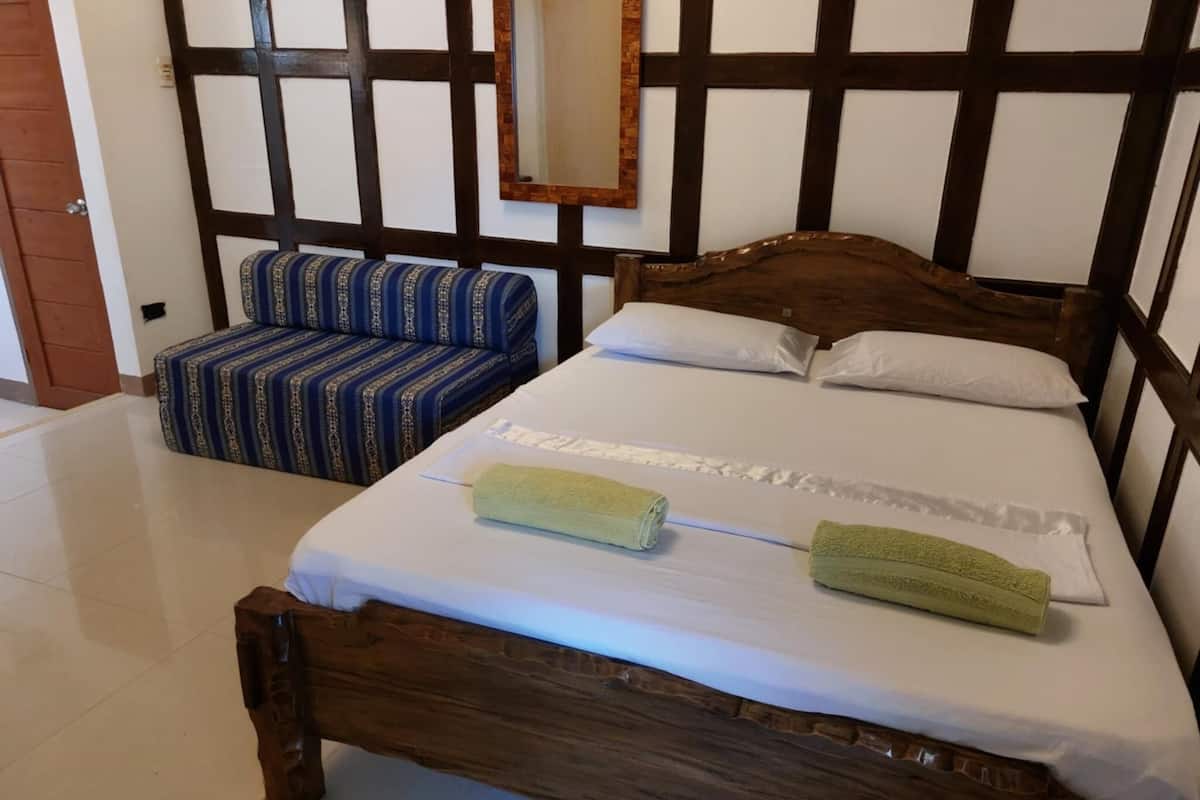Un lit avec une tête de lit en bois, un canapé à rayures bleues et un miroir au mur.