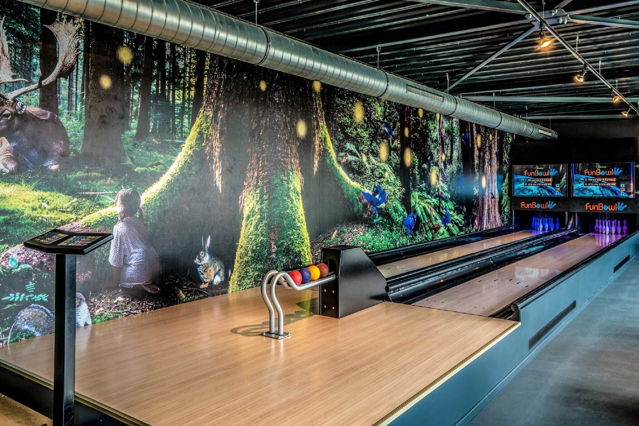 Een bowlingbaan met een digitale bosmuur, een bowlingbaan en een FunBowl bord.