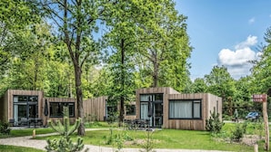 A modern wooden cabin with glass doors, outdoor seating, and a well-maintained garden. - Spacious Villa in Forest Park (Schaijk)