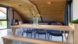 Ein moderner Essbereich mit einem Holztisch, schwarzen Stühlen und einer Blumenvase.